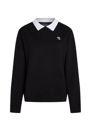 Μαύρο πουλόβερ με μακριά μανίκια, λευκό γιακά και μικρό λογότυπο με πρόσωπο που φοράει γυαλιά ηλίου στο πάνω αριστερό μέρος του στήθους.