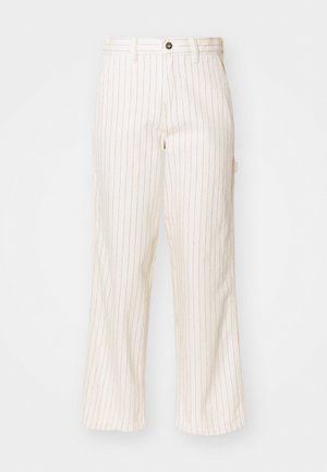 Pantalons larges en tissu crème avec de fines rayures verticales rouges. Dotés d'une fermeture à bouton et de poches avant, texture lisse.