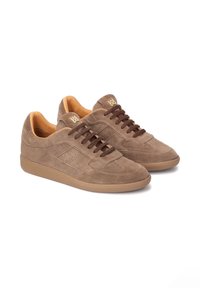 Beez-suede tossud, millel on pruunid nöörid ja kummist talla, külgedel läbivajutatud detailid ning helepruun sisemus.