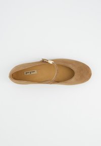 Béžové baleríny z broušené kůže s kulatou špičkou a kotníkovým páskem zdobeným kovovou sponou. Měkká vnitřní podšívka a hladká textura.