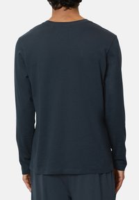 Long-sleeve navy shirt made from soft fabric, featuring a classic crew neckline and a relaxed fit, with a smooth texture and minimal detailing.