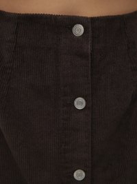 Jupe en velours côtelé marron affichant des côtes verticales, une taille haute et des boutons-pression argentés sur le devant pour la fermeture.