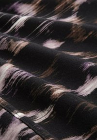 Schwarzer Stoff mit einem welligen, abstrakten Muster in Brauntönen und Lila. Die Textur wirkt glatt mit einem subtilen Glanz. Die Ränder sind sauber verarbeitet.