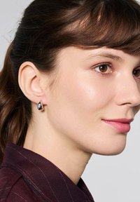 Srebrne kolczyki w kształcie kropli, z czarnym akcentem i przezroczystym kamieniem. Gładkie wykończenie, prezentujące geometryczny kształt.