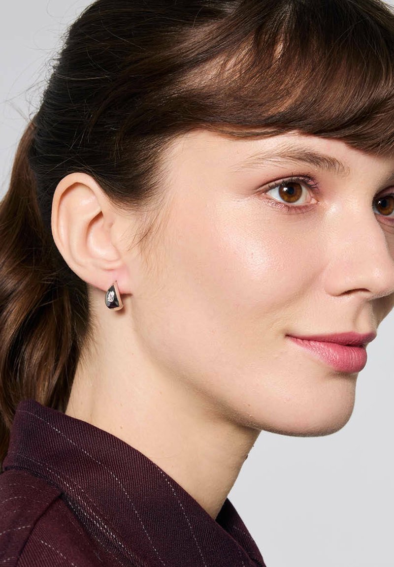 Srebrne kolczyki w kształcie kropli, z czarnym akcentem i przezroczystym kamieniem. Gładkie wykończenie, prezentujące geometryczny kształt.