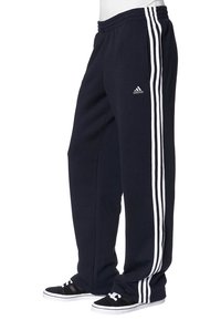 Tmavě modré joggingové kalhoty Adidas se třemi bílými pruhy po stranách, elastický pás, nošené s černobílými teniskami.