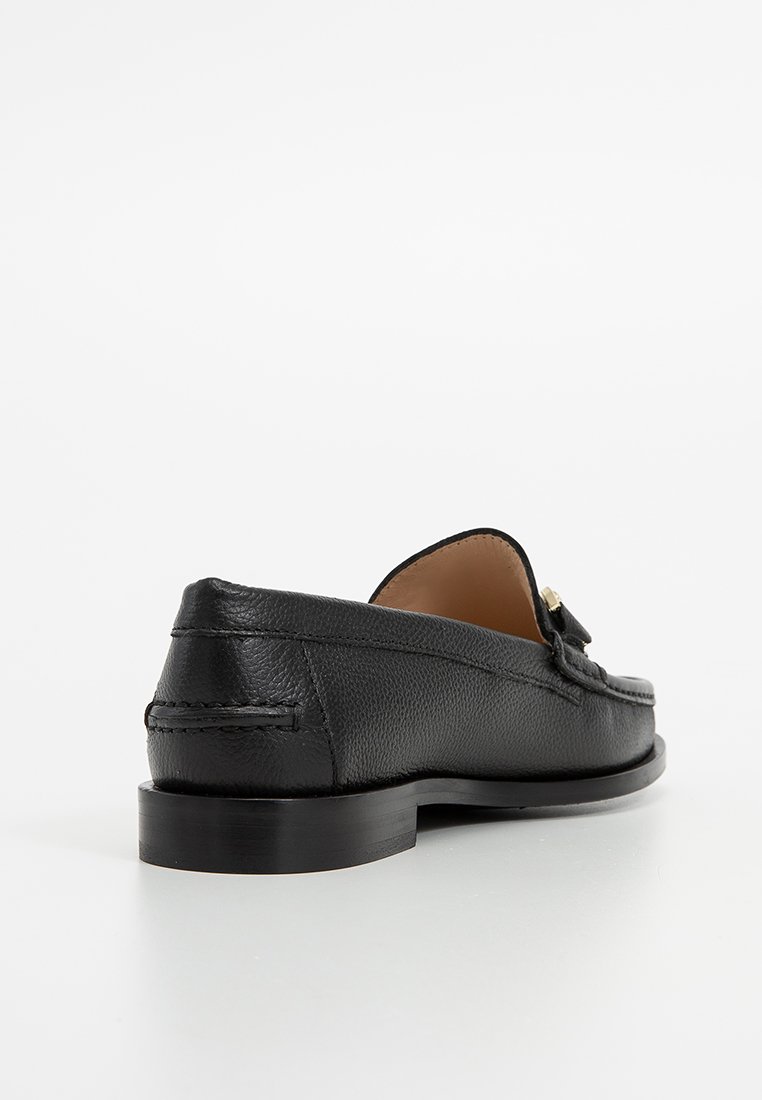 Czarne skórzane loafersy o teksturowanym wykończeniu, z zaokrąglonym noskiem i niskoprofilową podeszwą. Charakteryzują się dyskretnym przeszyciem oraz dekoracyjnym akcentem.
