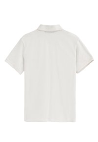 Polo de manga corta en algodón color beige claro, con un cuello clásico y una tela suave y texturizada. Sin logos ni patrones visibles.