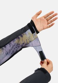 Ski jacket with a black exterior, purple and gold patterned interior. Features Velcro straps and a snug cuff design for warmth and fit.