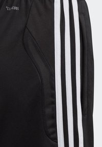 Pantalones cortos deportivos negros con franjas laterales blancas, que cuentan con un panel texturizado y una cinturilla elástica para mejorar la comodidad y el ajuste.