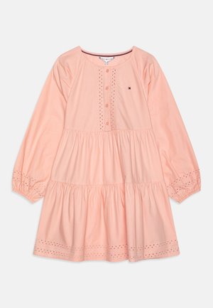 Vestido de algodón melocotón con mangas largas, cierre de botones en la parte delantera, detalles de bordado en ojales y diseño de falda de capas. Presenta un pequeño logo en el pecho.
