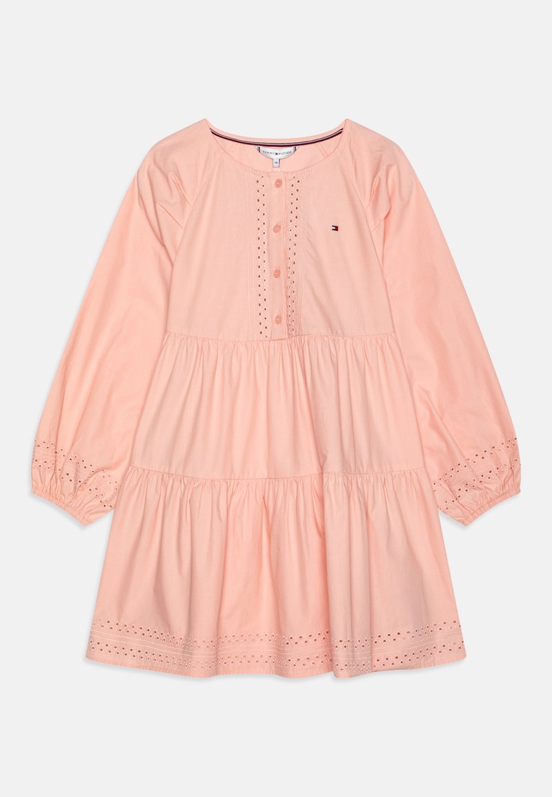 Persikofärgad bomullsklänning med långa ärmar, knapplist fram, broderade ögondetaljer och en tierad kjoldesign. Har en liten logotyp på bröstet.