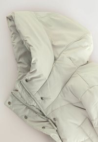 Pufjakke i lysegrå med hætte, featuring et quiltet design, frontlynlås og trykknapper til sikker lukning.