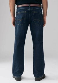 Jeans de mezclilla azul oscuro con corte recto, que presentan dos bolsillos traseros con acentos de costura y un cinturón marrón visible en la cintura.