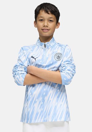 Ljusblå zip-up träningsjacka med kort ståkrage, som har subtila diagonala ränder och Manchester City-logotypen på vänster bröst.