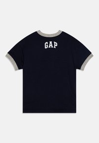 Marineblå t-skjorte med grå detaljer på kragen og ermene. "GAP" trykket i hvitt på ryggen, kort erm, og en avslappet passform.