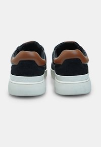 Mustad tossud sametist ja võrkkangast, pruunidest nahast aktsentidega ning paksu valge kummist tallaga. Omab pehmendatud kannakaitset mugavuse tagamiseks.