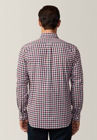 Camicia a maniche lunghe a quadri in rosso, bianco e blu navy. Presenta un colletto classico, polsini con bottone e un orlo dritto. Vista posteriore mostrata.