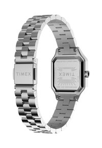 Nerūdijančio plieno laikrodis su aštuonkampiu ciferblatu, sidabrine apyranke ir poliruota įranga. Ant segtuko ir laikrodžio nugarėlės pažymėta "TIMEX".