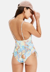 Maillot de bain une pièce avec un motif de fruits multicolores, des bretelles fines et ajustables, et un design à taille haute avec fronces sur les côtés.