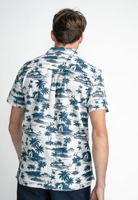 Chemise à manches courtes en gris clair avec un imprimé tropical bleu représentant des palmiers, des maisons et des bateaux. Fabriquée en tissu respirant.