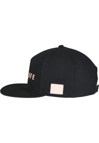 Sort kasket med flad skygge, med pink broderet tekst på forsiden og et lille pink logo-patch på bagsiden. Struktureret design og stoftekstur.