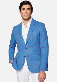 Niebieska marynarka w kratę, wykonana z teksturowanej tkaniny, z zapięciem na dwa guziki, kieszenią piersiową i mankietami na guziki, w zestawie z białą koszulą.