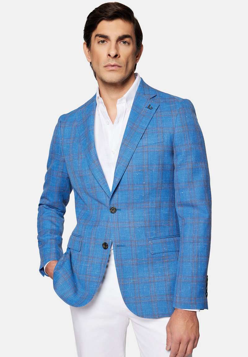 Niebieska marynarka w kratę, wykonana z teksturowanej tkaniny, z zapięciem na dwa guziki, kieszenią piersiową i mankietami na guziki, w zestawie z białą koszulą.