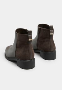 Bruna läderankelboots med en slät ovansida, mockapaneler, bakre dragkedja och en låg klack med texturerad sula.