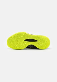 Semelle de chaussure jaune vif avec des motifs de bande de roulement en zigzag et linéaires complexes et un petit swoosh Nike près de la zone des orteils.