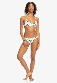 Conjunto de bikini floral que presenta un top en triángulo y una parte inferior con lazo lateral ajustable. Los colores incluyen tonos pastel con acentos en azul oscuro. El material parece suave.