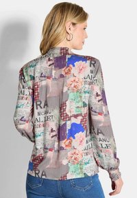 Langarmblouse met een bloemen- en patroonprint, voorzien van verschillende texturen, zacht stof en geplooide manchetten. Multikleurig met een lichte uitstraling.