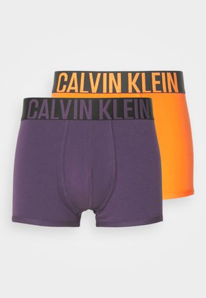Deux paires de boxers Calvin Klein. L'une est violette avec une taille noire, l'autre est dégradée orange avec une taille noire.