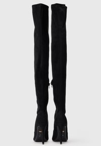 Melnas zamšādas augstas līdz gurniem zābaki ar šauru piegriezumu, augstiem stiletto papēžiem un sānu rāvējslēdzējiem ērtai uzvilkšanai. Pabeigti ar gludu struktūru.