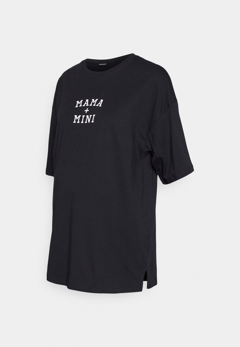 Black cotton t-shirt with short sleeves, round neckline, and side slits. Features white text: “MAMA + MINI” across the front.