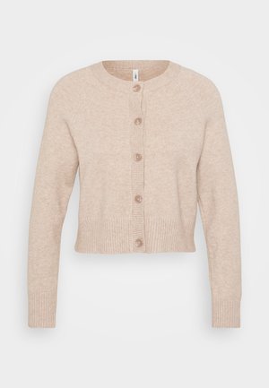 Iesietas bežīgas kardigāns, kas izgatavots no mīkstas auduma ar ribinātām piedurknēm un apakšmalu, ar sešiem lieliem pogām priekšā. Vienkāršs, klasiskā dizaina.