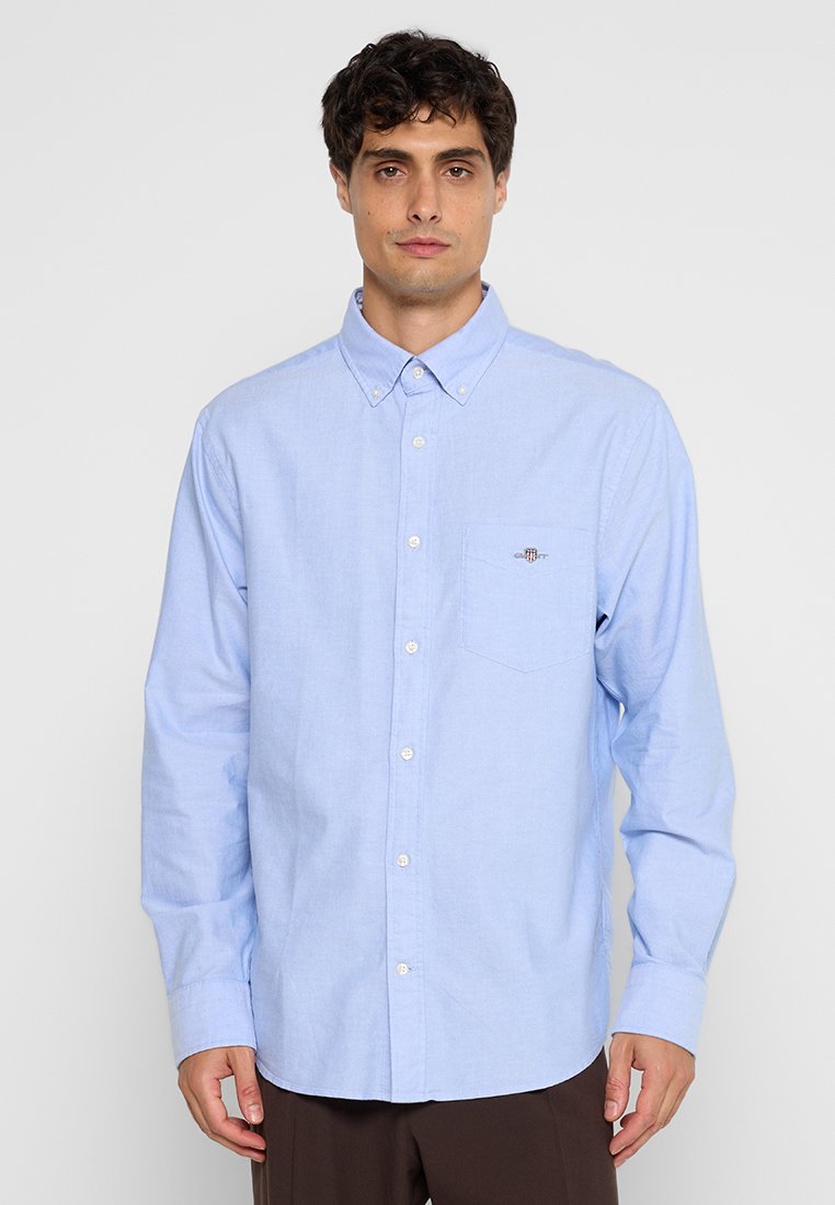Jasnoniebieska koszula zapinana na guziki z długimi rękawami, wykonana z bawełny, z kieszenią na piersi i małym wyszywanym logo na kieszeni.