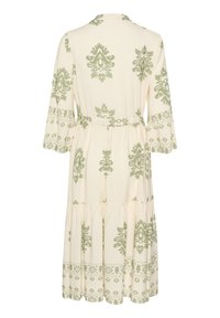 Short-sleeved, cream dress with green floral patterns. Features a tiered skirt and a waist tie. Made from lightweight, soft fabric.