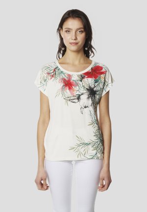 Fehér rövid ujjú póló színes virágmintákkal, piros és fekete színekben, zöld levelekkel. Puha anyag, kényelmes szabás.