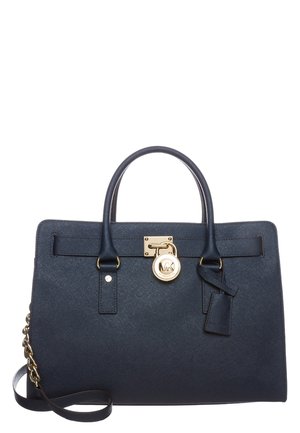 Navy blue leather handbag with two handles, gold lock and charm, and a detachable shoulder strap with chain detailing.