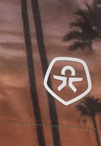 Vitt logotyp på en texturerad tyg med en gradient av varma färger och bilder av palmträd. Innehåller en sköldform runt logotypen.