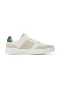 Sneaker bianca con accenti beige e crema, materiali in rete testurizzata e suede, punta tonda, suola in gomma e una linguetta verde sul tallone.