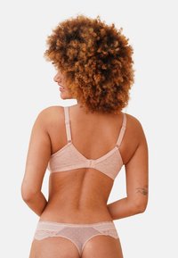 Pink lace bra features intricate patterns and adjustable straps, paired with a matching pink sheer polka-dot thong.