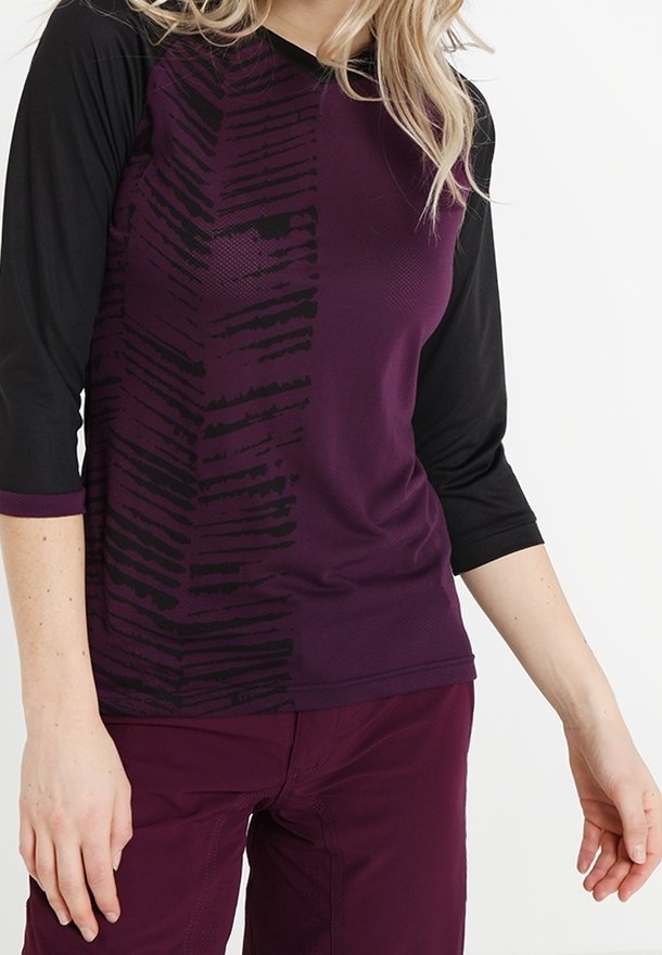 Lila und schwarze Dreiviertelarm-Bluse mit einem strukturierten vertikalen Muster auf einer Seite und einer glatten Oberfläche auf der anderen.