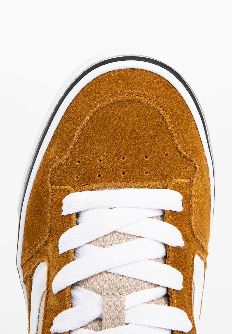 Zapatilla de ante color tan con cordones blancos, lengüeta de malla y ribete negro. Presenta perforaciones a lo largo de la puntera y una superficie texturizada.