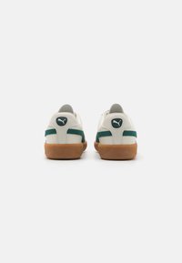 Sneaker bianche con accenti verdi, pannelli in suede texturizzati, suole in gomma e lacci piatti. Presentano un logo circolare sul tallone e un colletto imbottito.