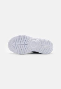 Valkoinen tennarin pohja, jossa on kalanruoto-kuvio ja ympyrän muotoinen Nike-logo keskellä yksinkertaisella valkoisella taustalla.
