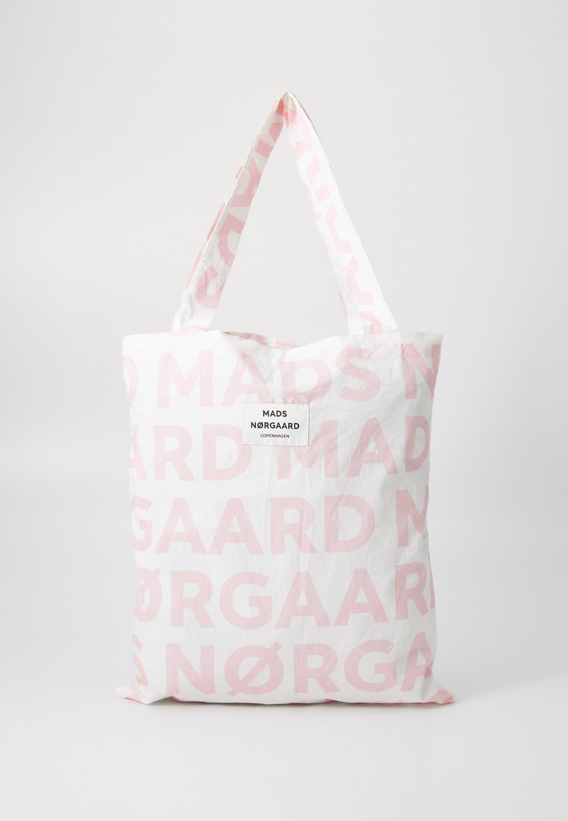 Tote bag made of white fabric featuring large pink text reading "MADS NØRGAAARD." It has two sturdy handles and a rectangular shape.