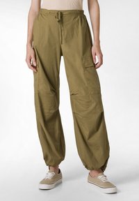 Pantaloni cargo verde oliva con vita elastica e orli elasticizzati, dotati di tasche laterali, realizzati in tessuto leggero con una vestibilità rilassata.