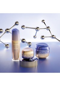 Tre Shiseido hudvårdsburkar: en hög, klar flaska med ett lila lock, en rund burk med guld-accenter och en blå burk med en glittrande yta.